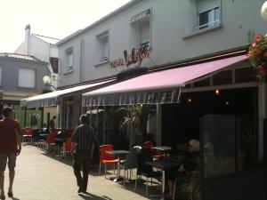 a group of people walking down a sidewalk outside a cafe at Le Ceïtya in Saint-Gilles-Croix-de-Vie