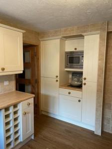 a kitchen with white cabinets and a microwave at Serendipity in Pateley Bridge
