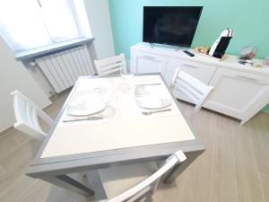 een witte eettafel met stoelen en een televisie bij Appartamento Il Castello in Casale Monferrato