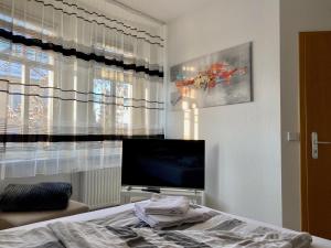 um quarto com uma televisão, uma cama e uma janela em Blue Max Parkzimmer em Grossenhain
