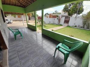 two green chairs on a porch with a yard at Pousada Marlene in Barreirinhas