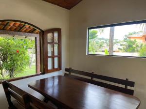 a dining room with a wooden table and two windows at Casa de 5 suítes e piscina em Geribá in Búzios