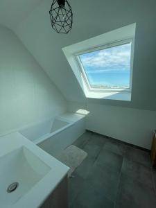 ein weißes Bad mit einem Fenster und einem Waschbecken in der Unterkunft Maison neuve, chaleureuse, vue sur L'Aber Benoït in Saint-Pabu