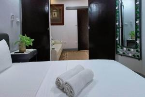 Una cama blanca con una toalla encima. en 5 - Cabanatuan City's Best Bed and Breakfast Place en Cabanatuan