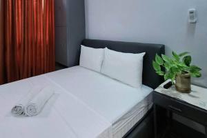 um quarto com uma cama com lençóis brancos e uma planta em 5 - Cabanatuan City's Best Bed and Breakfast Place em Cabanatuan