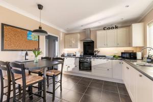 a kitchen with white cabinets and a table and chairs at Willow Lodge, Wolfscastle in Haverfordwest