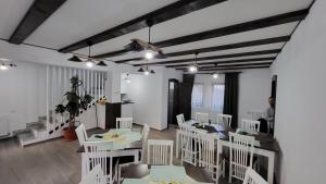 comedor con sillas blancas y mesa en PENSIUNEA CASTELANA, en Racoşu de Jos