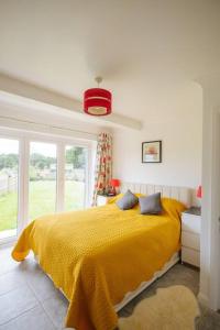 um quarto com uma cama amarela e uma janela em Blackberry Annex. Detached cottage. Rural location em West Chiltington
