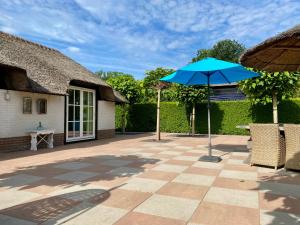 un patio con sombrilla azul y sillas en Vakantie huis Ermelo, en Ermelo