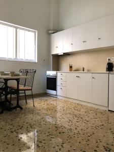 uma cozinha com armários brancos, uma mesa e uma sala de jantar em Graffiti Ground Floor em Atenas