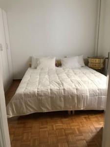 a white bed in a bedroom with a wooden floor at Graffiti Ground Floor in Athens