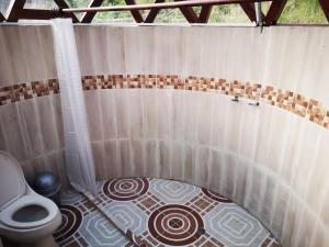 a bathroom with a toilet and a tiled floor at Tybyn Geo Lodge in Arcabuco