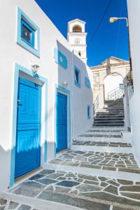 a building with blue doors and stairs with a clock tower at Maria House in Karpathos Town