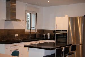 uma cozinha com bancadas pretas e um frigorífico de aço inoxidável em A l’orée du Vuache 