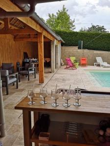 eine Gruppe Weingläser auf einem Tisch neben einem Pool in der Unterkunft Le Plouf des Gargouilles in Onet le Château