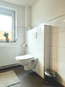 a white bathroom with a toilet and a window at FeWo Lichtblick in Mengen