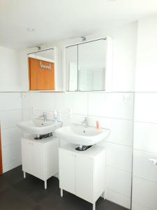 a white bathroom with two sinks and a mirror at FeWo Lichtblick in Mengen