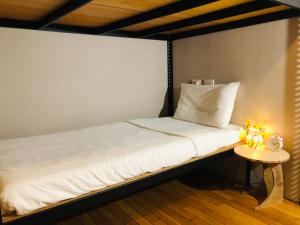 - un lit dans une chambre avec une table de chevet dans l'établissement Hostel of Rising Sun 昇行旅, à Taipei