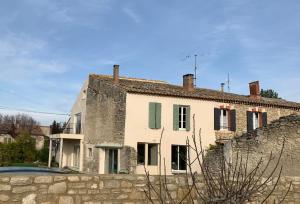 a white house with a stone wall in front of it at Clos du Cardinal avec piscine in LʼIsle-sur-la-Sorgue