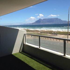 a balcony with a view of the beach and the ocean at Beachfront Apartment at Seaspray in Blouberg in Bloubergstrand