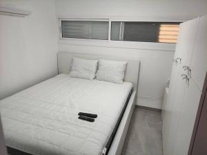 a small white bed in a small room with a window at יחידת אירוח חדשה ומקסימה בכרמיאל in Karmiel