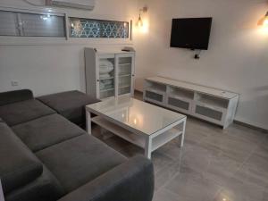 יחידת אירוח חדשה ומקסימה בכרמיאל في كرمئيل: غرفة معيشة مع أريكة وتلفزيون
