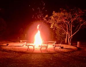 uma fogueira num parque à noite com dois bancos em Pousada/Camping Mirante Serrano em Alto Paraíso de Goiás