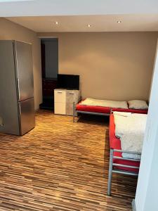 a room with two beds and a refrigerator and a chair at Appartments Casa del Sol in Braunschweig