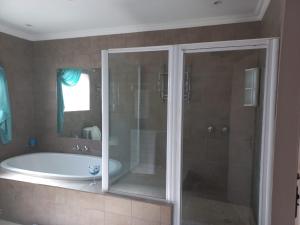 a bathroom with a tub and a glass shower at LISA VILLAGE in Bloemfontein