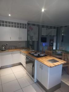 a kitchen with white cabinets and a wooden counter top at LISA VILLAGE in Bloemfontein