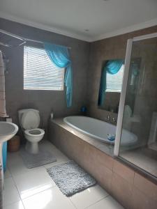 a bathroom with a tub and a toilet and a sink at LISA VILLAGE in Bloemfontein