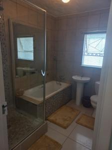 a bathroom with a shower and a tub and a toilet at LISA VILLAGE in Bloemfontein