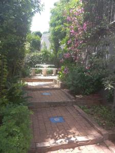 a garden with a bench and some pink flowers at LISA VILLAGE in Bloemfontein