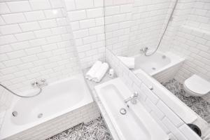 a white bathroom with a tub and a sink and a toilet at Mokotowska Place for You in Warsaw