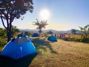 três tendas num campo com o sol ao fundo em Pousada/Camping Mirante Serrano em Alto Paraíso de Goiás
