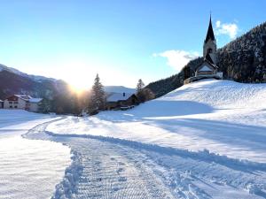 a snow covered road with a church in the background at Sonnige Panorama Aussicht bei Davos Lenzerheide in Schmitten