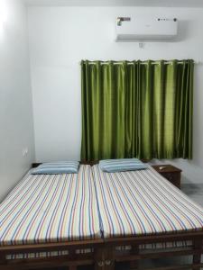 Bett in einem Zimmer mit grünem Vorhang in der Unterkunft Jayuz Homestay & Foodies in Kozhikode