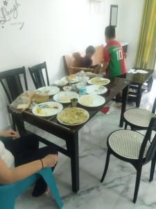 einen Tisch mit Tellern und Menschen, die um ihn herum sitzen in der Unterkunft Jayuz Homestay & Foodies in Kozhikode