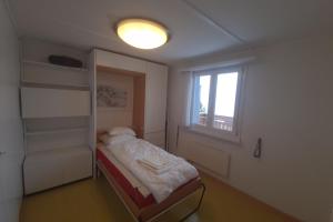 a small bedroom with a bed and a window at Cozy Corner - CharmingStay in Flumserberg