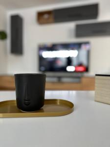 a black coffee cup sitting on a tray on a counter at ESI Apartments #Central in Timişoara