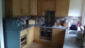 a kitchen with wooden cabinets and a blue refrigerator at Millstone cottage in Oldham