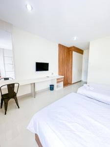 a white bedroom with a bed and a desk with a tv at Pillow Guest House in Balikpapan