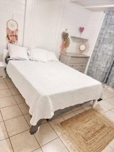 ein Schlafzimmer mit einem großen Bett mit weißer Bettwäsche in der Unterkunft villa La Mérédith in Le Lamentin