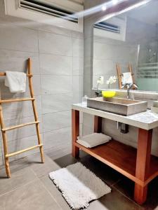 ein Bad mit einem Waschbecken und einem Spiegel in der Unterkunft villa La Mérédith in Le Lamentin