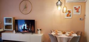 een woonkamer met een tv en een tafel met stoelen bij DN Rose Apartmant in Boedapest