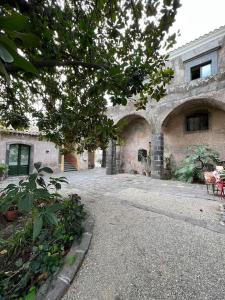 un grande edificio in pietra con un cortile di fronte di Puleera a San Leonardello