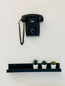 um telefone preto pendurado numa parede com plantas em Appartamento Gemma em Pietrasanta