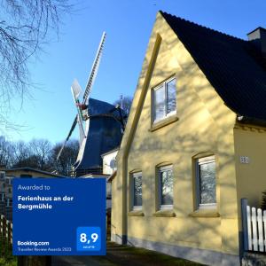 una casa con un cartel delante de un molino de viento en Ferienhaus an der Bergmühle en Flensburg