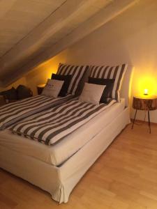a large white bed with striped pillows in a room at Chiemgau-LOFT zwischen Seenzauber und Gipfelglück in Riedering