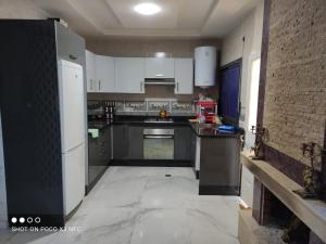 a kitchen with white cabinets and a tile floor at Super Chalet à Imouzzer kendar. in Imouzzer Kandar